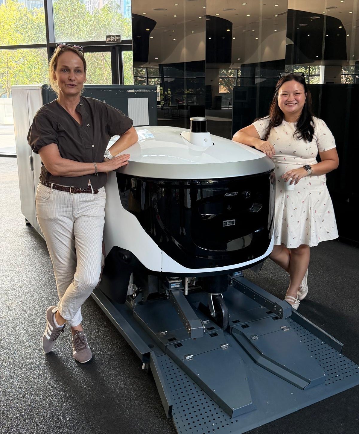 Two members of the Risky Tuesday team standing either side of a Viabot outdoor cleaning robot.